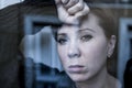 Dramatic close up portrait of young beautiful woman thinking and feeling sad suffering depression at home window looking depresse