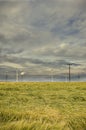 Dramatic cloud sky over cornfield with dark rain clouds and power lines and wind turbines Royalty Free Stock Photo