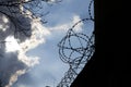 Dramatic clouds behind barbed wire fence on prison wall Royalty Free Stock Photo