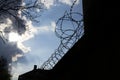 Dramatic clouds behind barbed wire fence on prison wall Royalty Free Stock Photo