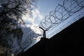 Dramatic clouds behind barbed wire fence on prison wall Royalty Free Stock Photo