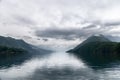 Dramatic clouds cast a majestic reflection on the still waters of a Norwegian fjord