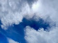 Dramatic clouds frame a deep blue opening in the sky, with bright sunlight breaking through the top right. A striking contrast Royalty Free Stock Photo