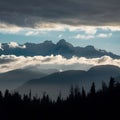 Dramatic clouds frame mountain peaks and towering trees in silhouette Royalty Free Stock Photo