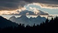 Dramatic clouds frame mountain peaks and towering trees in silhouette Royalty Free Stock Photo