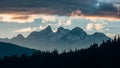 Dramatic clouds frame mountain peaks and towering trees in silhouette Royalty Free Stock Photo