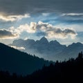 Dramatic clouds frame mountain peaks and towering trees in silhouette Royalty Free Stock Photo