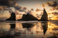 Dramatic clouds over sea stacks in Oregon at sunset with reflection in sand.