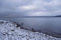 Dramatic clouds over winter lake scene with snowy shore Royalty Free Stock Photo