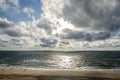 Dramatic clouds and sunlight reflecting on the North Sea at a wide beach with few people on the island of Sylt in Germany