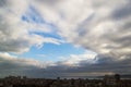 Dramatic cloudscape over the seaside city. Dark clouds surround the last spot of a blue sky in a daytime