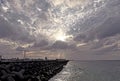 Dramatic cloudy sky over a tetrapod breakwater with distant city skyline and ocean Royalty Free Stock Photo