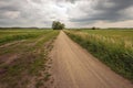 Dramatic cloudy sky over a winding gravel road in a rural landscape Royalty Free Stock Photo