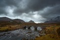 Dramatic cloudy sky with river and old bridge over the River Sligachan on the Isle of Skye Scotland with the Cuillin mountain Royalty Free Stock Photo