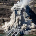 Dramatic controlled demolition expertly collapses large concrete highway bridge structure into massive dust cloud. Royalty Free Stock Photo