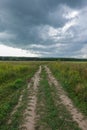 Dramatic countryside landscape with thunderclouds in the sky over a wheat field. country road in the field Royalty Free Stock Photo