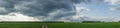 Dramatic countryside landscape with thunderclouds in the sky over a wheat field. panorama