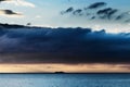 Dramatic dark nimbostratus cloud formation over Baltic sea and small ship silhouette.