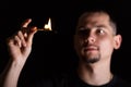 Dramatic dark portrait of man and lit match fire over black background Royalty Free Stock Photo