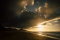 Dramatic dark shadows sunset at the beach with black mountains in background - sun and ocean for adventure concept - scenic Royalty Free Stock Photo