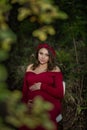 Dramatic dark woodsy outdoor portrait of 9 month old pregnant women holding belly