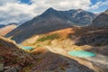 Dramatic foggy landscape with sunlit sharp mountain ridge with blue glacier lakes under low clouds at changeable weather.