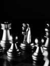 Dramatic grayscale shot of chess figures lit in the darkness