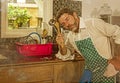 Dramatic grunge portrait of 30s to 40s house husband or single man in kitchen apron doing domestic chores washing dishes or