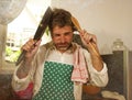 Dramatic grunge portrait of 30s to 40s house husband or single man in kitchen apron doing domestic chores washing dishes or