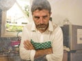 Dramatic grunge portrait of 30s to 40s house husband or single man in kitchen apron doing domestic chores washing dishes or