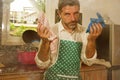 Dramatic grunge portrait of 30s to 40s house husband or single man in kitchen apron doing domestic chores washing dishes or