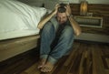 Dramatic home portrait of young desperate and depressed lonely man sitting on bedroom floor crying sick suffering anxiety crisis Royalty Free Stock Photo