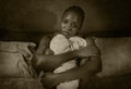 Dramatic home portrait of young sick and depressed black afro American girl sitting on bed upset and sleepless at night feeling