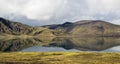 Dramatic iceland landscape with a green hill and black lava and and blue mirror mountain lake. Iceland