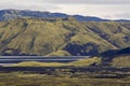 Dramatic iceland landscape with a green hill and black lava and and blue mirror mountain lake. Iceland