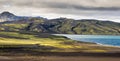 Dramatic iceland landscape with a green hill and black lava and and blue mirror mountain lake. Iceland