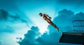 Athletic Man Diving from Platform Against Dramatic Blue Sky and Cloud Background Royalty Free Stock Photo