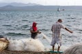 Dramatic image of dominican fishermen on caribbean coast pulling in their nets with windmills in background.