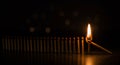 A row of standing matches with one match lit and falling to the right side with ia Royalty Free Stock Photo