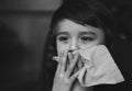 Dramatic image of Sick kid blowing nose into tissue, Unhealthy child suffering from running nose or sneezing and covering his nose