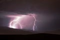 Dramatic image of a stormy sky above a mountain range, illuminated by a brilliant lightning bolt Royalty Free Stock Photo