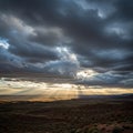 A dramatic landscape features a vast, arid terrain under a sky filled with thick, dark Royalty Free Stock Photo