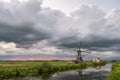 Dramatic landscape image of a windmill in Holland under a beautiful dark sky