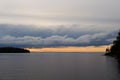 Dramatic large clouds over lake during orange sunset. Silhouettes of islands on the horizon Royalty Free Stock Photo