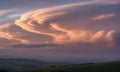 Dramatic Lenticular Cloud Formation Over Rolling Green Hills in Sunset: A Captivating Display of Atmospheric Optics and Royalty Free Stock Photo