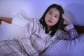 Dramatic lifestyle portrait of young attractive sad and depressed Asian Chinese woman on bed awake at night feeling stressed and Royalty Free Stock Photo