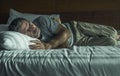 Dramatic lifestyle portrait of young attractive sad and depressed man lying on bed at home bedroom thoughtful and pensive feeling Royalty Free Stock Photo