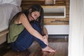 Young depressed and sad Asian Japanese woman sitting on floor at bedroom next to bed suffering depression problem and anxiety