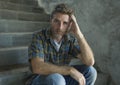 Dramatic lifestyle portrait of young depressed and sad man sitting alone outdoors on dark street staircase suffering depression Royalty Free Stock Photo