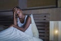 Dramatic lifestyle portrait of young sad and depressed black afro American woman on bed sleepless suffering headache insomnia slee